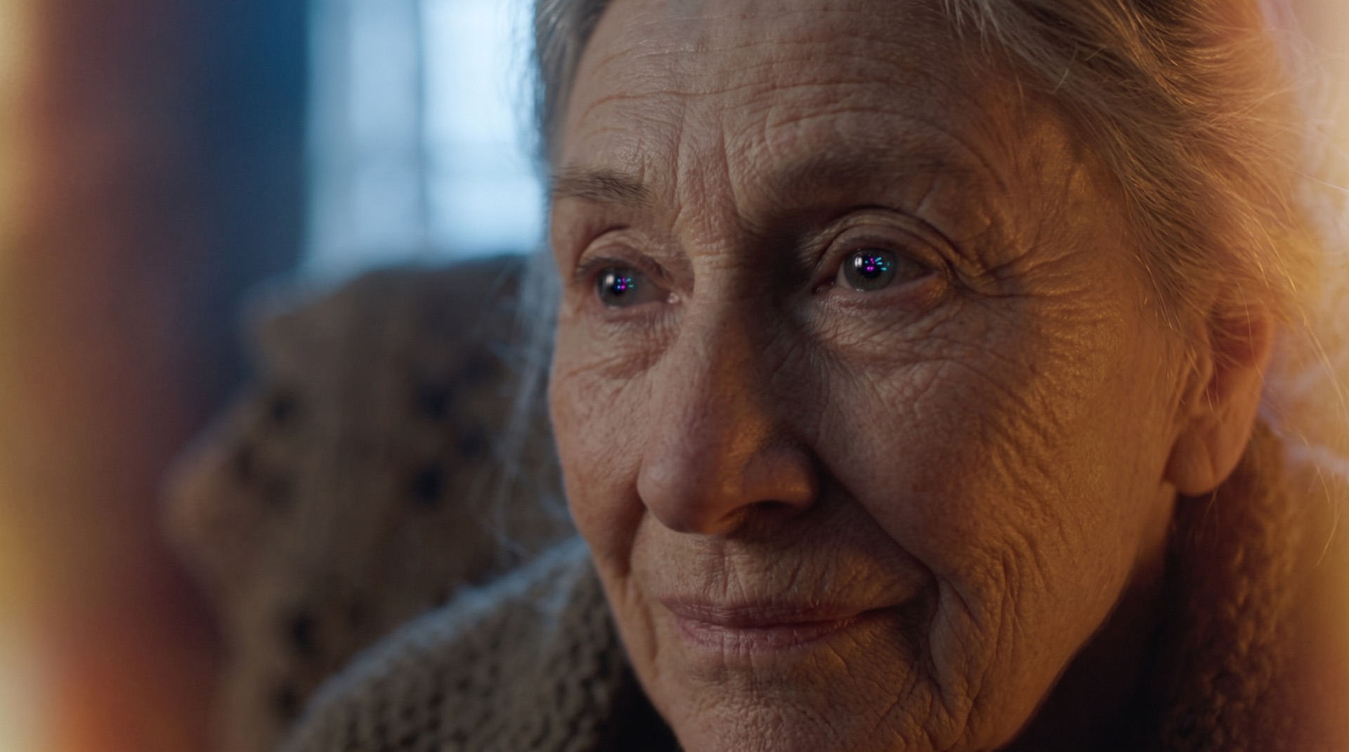 An older woman's eyes, festival light reflected in them